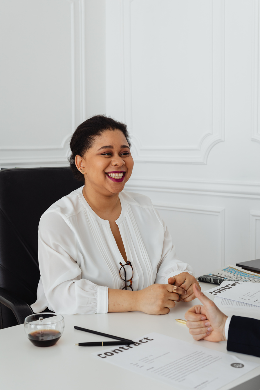 Happy Woman in White Long Sleeves Sitting on the Table 